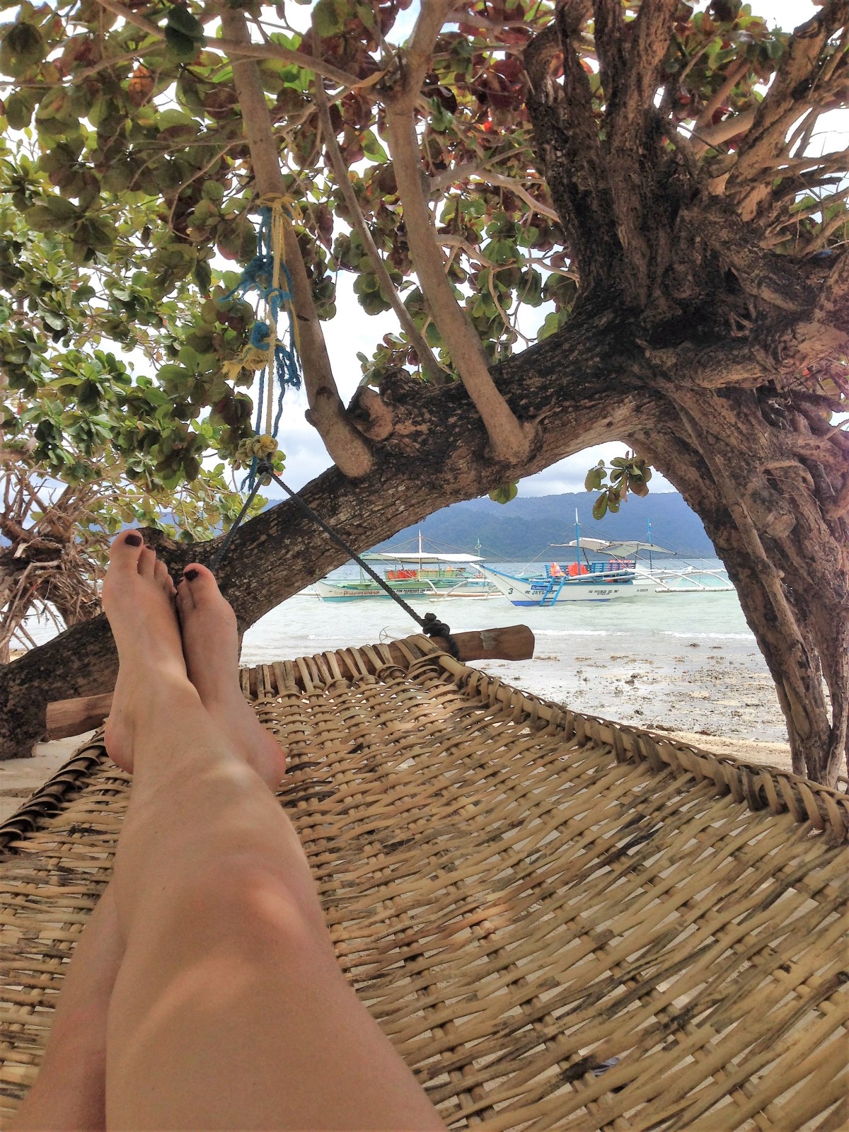 girl lying in a hammock on a beach in the philippines